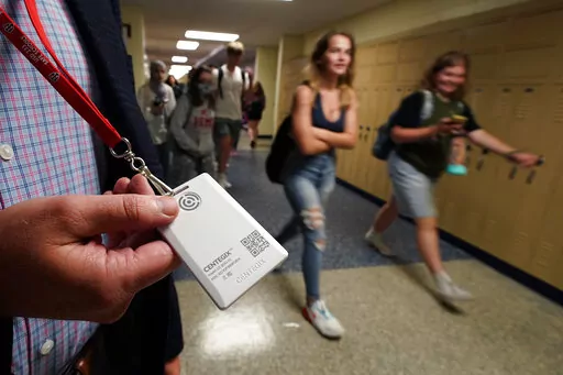 Brent Kiger, Olathe Public Schools' director of safety service, displays a panic-alert button while students at Olathe South High School rush between classes Friday, Aug. 19, 2022, in Olathe, Kan. The district introduced the buttons, which allow staff to trigger a lockdown that will be announced with flashing strobe lights, a takeover of staff computers and a prerecorded intercom announcement, at the start of this school year as part of $2.1 million plan to make district schools more secure. (AP