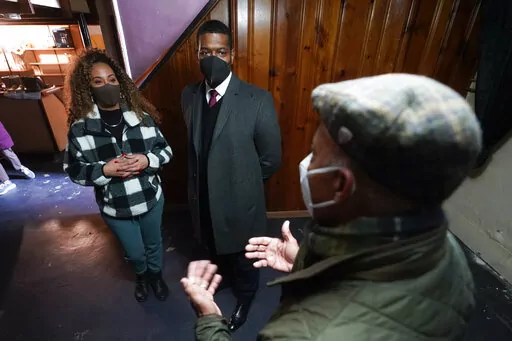 Tilicia Owens and Environmental Protection Agency Administrator Michael Regan, center, listen to Detroit Water and Sewerage Department director Gary Brown in her basement Friday, Feb. 18, 2022, in Detroit. They discussed the city’s $15 million effort to provide flood prevention pumps and other equipment in 11 neighborhoods. Part of the money will come from the $350 billion Coronavirus State and Local Fiscal Recovery Funds which can be used by states, counties and cities to recover from the pan
