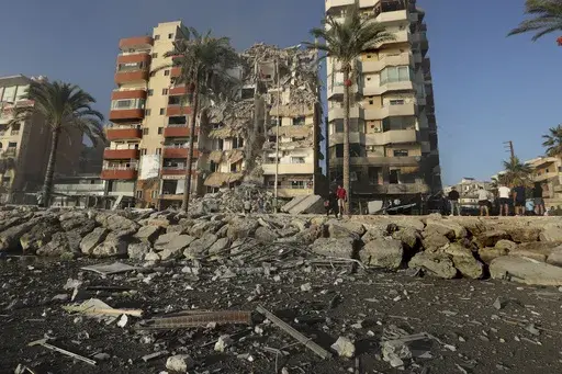 People gather in front of a destroyed building hit in an Israeli airstrike in Tyre, Lebanon, Monday, Oct. 28, 2024.(AP Photo/Mohammed Zaatari)