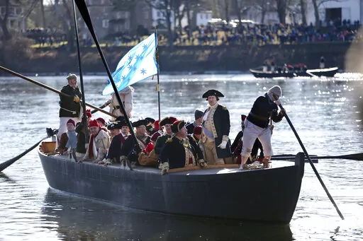FILE - John Godzieba, as Gen. George Washington, second right, stands in a boat during a re-enactment of Washington's daring Christmas 1776 crossing of the Delaware River in Washington Crossing, Pa., on Dec. 25, 2016.  Spectators were once again being invited to gather along the Delaware River to watch an annual reenactment of George Washington’s crossing of the Delaware River on Christmas Day, Saturday, Dec. 25, 2021,  a year after an online re-enactment was posted instead. (AP Photo/Mel Evan