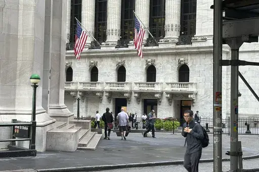 People pass the New York Stock Exchange, at rear, on Aug. 27, 2024, in New York. (AP Photo/Peter Morgan, File)