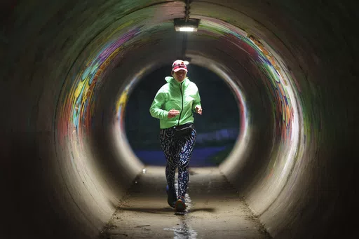 Ultra runner Helen Ryvar runs through an underpass in Wrexham during running a half marathon in Wrexham, Wales, Wednesday, March 20, 2024. Helen who took up running in 2020 just before lockdown completes her daily half marathon early so as to fit in a full time job and being a single parent to 3 children. (AP Photo/Jon Super)