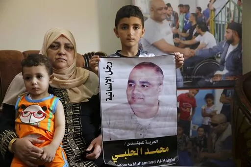 Amal el-Halabi holds her grandson Fares while her grandson Amro, 7, holds a picture of his father Mohammed el-Halabi, Gaza director of the international charity World Vision, who is detained and accused by Israeli security of diverting sums to Hamas that exceed its total budget, at his family house in Gaza City, Aug. 8, 2016. In May 2022, nearly six years after Israel accused Mohammed el-Halabi of diverting tens of millions of dollars from an international charity to Gaza's militant Hamas rulers