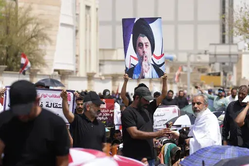 Supporters of Shiite cleric Muqtada al-Sadr with his poster gather during an open-air Friday prayers near the parliament building in Baghdad, Iraq, Friday, Aug. 26, 2022. Al-Sadr's supporters continue their sit-in outside the parliament to demand early elections. (AP Photo/Hadi Mizban)