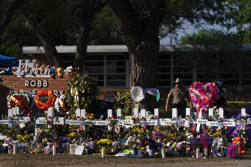 Flowers and candles are placed around crosses on May 28, 2022, at a memorial outside Robb Elementary School in Uvalde, Texas, to honor the victims killed in the school shooting a few days prior. Victims of the Uvalde school shooting that left 21 people dead have filed a lawsuit seeking $27 billion against local and state police, the city and other school and law enforcement officials for failing to follow active shooter protocol because authorities waited more than an hour to confront the attack