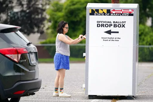 A woman drops a ballot into a drop box while casting her vote during Maryland's primary election, Tuesday, July 19, 2022, in Baltimore.  Whether a state requires voters to request an absentee ballot or participates in universal mail-in voting, all ballots cast by mail or dropped off at a drop box are vetted to ensure their legitimacy.(AP Photo/Julio Cortez, File)