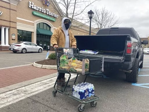 Chris Stokes picks up extra provisions at a grocery store in Norfolk, Va., on Friday Jan. 21, 2022, as the city prepares for an upcoming snowstorm.   (AP Photo/Ben Finley)