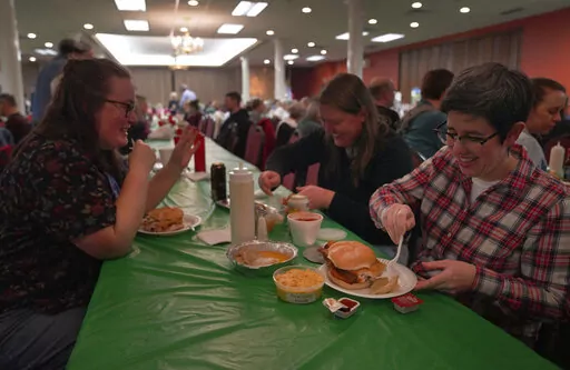 From left, Laura Kuster, Miranda Crotsley, and Hollen Barmer eat fish sandwiches, homemade perogies, and macaroni and cheese at the St. Maximilian Kolbe Catholic Church fish fry in the West Homestead neighborhood of Pittsburgh, on Friday, Feb. 24, 2023. To innovate the age-old tradition of fish fries, Barmer and volunteers from Code for Pittsburgh created the "Pittsburgh Lenten Fish Fry Map," an online interactive map that locates and documents active fish fries from year to year across Western 