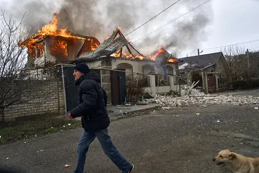 A local resident runs past a burning house hit by the Russian shelling in Kherson, Ukraine, on the Orthodox Christmas Eve Friday, Jan. 6, 2023. (AP Photo/LIBKOS)
