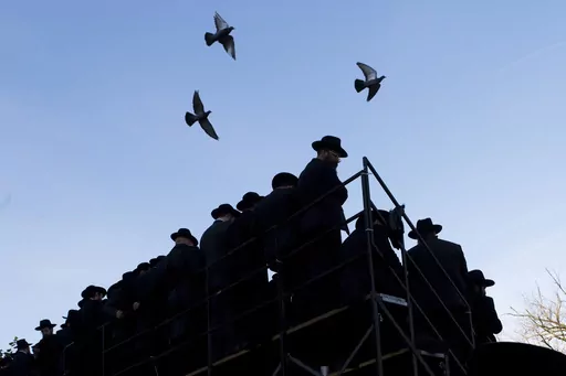 Pigeons fly above rabbis gathering for a group photo at the Chabad-Lubavitch World Headquarters, Sunday, Nov. 4, 2018, in New York. The synagogue in New York's Brooklyn borough is closely tied with Rabbi Menachem Mendel Schneerson's enduring influence in global Judaism and beyond in the three decades since his death, but it received unwanted attention in January 2024 with a brawl between some worshippers and police, part of a sequence of events that began with the discovery of a secretly dug tun