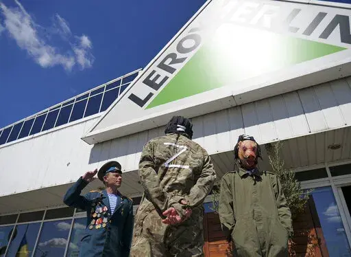 Activists, including Arkadiusz Szczurek, left, take part in a protest outside an outlet of French home improvement retailer Leroy Merlin in Warsaw, Poland, on Saturday May 7, 2022. In the weeks after Russia invaded Ukraine, a protest movement was born in Poland urging people to boycott companies that have chosen to keep operating in Russia. (AP Photo/Pawel Kuczynski)