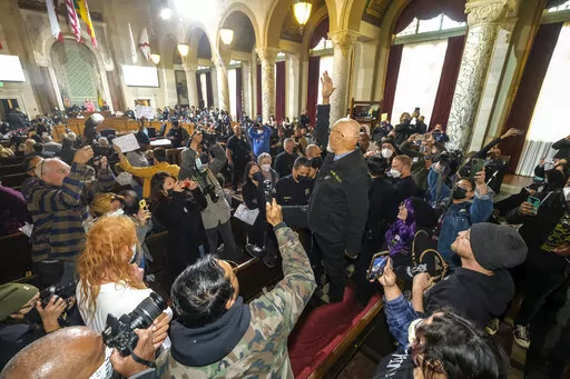A man stands on the bench and shouts slogans during the Los Angeles City Council meeting Tuesday, Dec. 13, 2022, in Los Angeles. A small group of protesters chanted during the meeting calling for the resignation of Councilman Kevin de Leon. (AP Photo/Ringo H.W. Chiu)