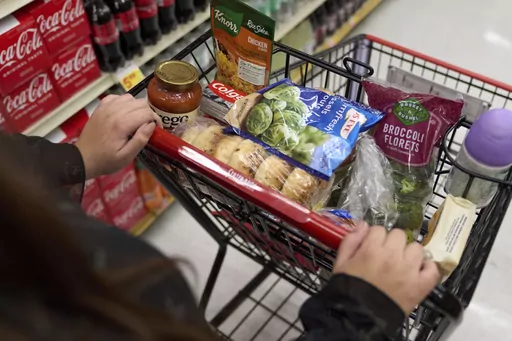 A food shopper pushes a cart of groceries at a supermarket in Bellflower, Calif., on Monday, Feb. 13, 2023. Preparing for a midnight toast and more year-end festivities may require a run or two to the store — but you’ll want to prepare for some limited business hours. (AP Photo/Allison Dinner, File)