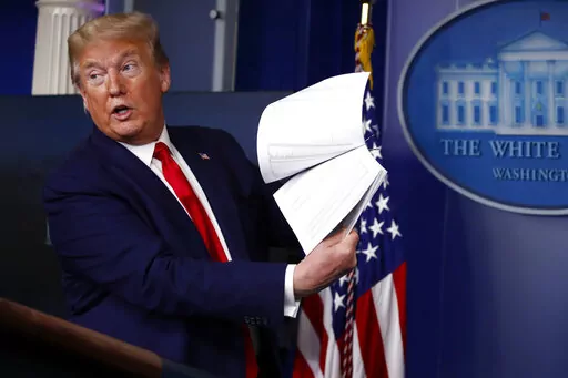 FILE President Donald Trump holds up papers as he speaks about the coronavirus in the James Brady Press Briefing Room of the White House on April 20, 2020, in Washington.  President Joe Biden is ordering the release of Trump White House visitor logs to the House committee investigating the riot of Jan. 6, 2021, once more rejecting former President Donald Trump’s claims of executive privilege. The committee has sought a trove of data from the National Archives, including presidential records th