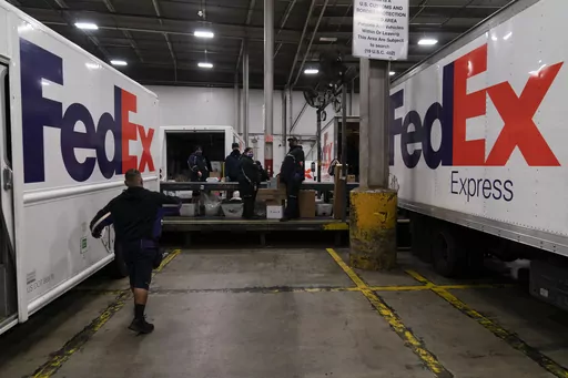 FedEx delivery trucks are parked next to a conveyor belt while being loaded with packages for delivery at the FedEx regional hub at the Los Angeles International Airport in Los Angeles, Dec. 7, 2021. Carriers like the U.S. Postal Service, FedEx and United Parcel Service have capacity to meet projected demand this holiday season, which is cheery news for shippers and shoppers alike. (AP Photo/Jae C. Hong)