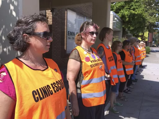 Escort volunteers line up outside the EMW Women's Surgical Center, on Monday, July 17, 2017, in Louisville, Ky. A pregnant woman in Kentucky who filed a lawsuit demanding the right to an abortion has learned her embryo no longer has cardiac activity, her attorneys said Tuesday, Dec. 12, 2023. Her attorneys didn't immediately comment on what effect the development would have on the lawsuit filed last week in a state court in Louisville. (AP Photo/Dylan Lovan, File)