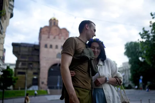 Stand-up comics Serhiy Lipko and Anastasia Zukhvala embrace during an interview with The Associated Press on their wedding day in Kyiv, Ukraine, Saturday, June 11, 2022. Lipko and Zukhvala are among those using humor as a weapon, and to keep spirits up. But he'll soon have a real weapon in his hands, because he's going into battle. (AP Photo/Natacha Pisarenko)