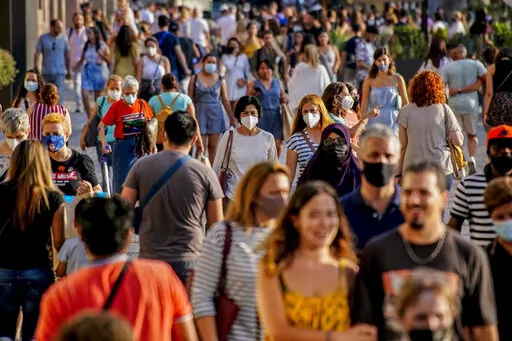 People wearing a face mask to protect against the spread of coronavirus walk along a street in downtown Barcelona, Spain, July 3, 2021. Some European countries such as Spain are making tentative plans for when they might start treating COVID-19 as an "endemic" disease, but the World Health Organization and other officials have warned that the world is nowhere close to declaring the pandemic over. (AP Photo/Joan Mateu, File)