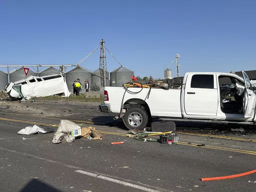 In this photo provided by KIFI Local News 8, a pickup truck crashed into a passenger van on U.S. Highway 20, Saturday, May 18, 2024, in Idaho Falls, Idaho. State police say the accident happened early Saturday morning when a pickup crossed the centerline on U.S. Highway 20 and fatally hit a passenger van. (Jeff Roper/KIFI Local News 8 via AP)