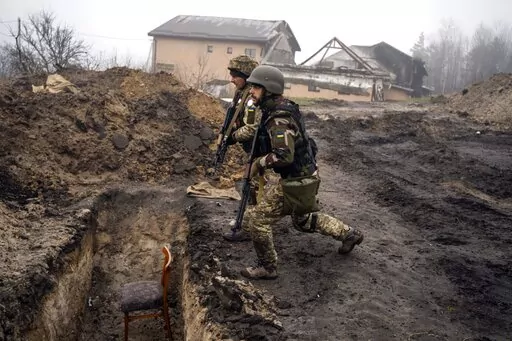 Ukrainian soldiers approach a trench that had been used by Russian soldiers as they retake an area on the outskirts of Kyiv, Ukraine, Friday, April 1, 2022. (AP Photo/Rodrigo Abd)