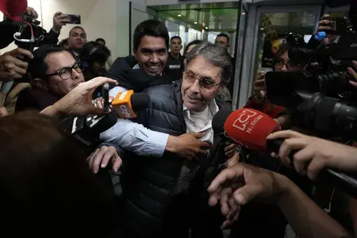 Media swarm Fabio Ochoa, center, a former member of Cartel of Medellin, upon his arrival at El Dorado airport, after being deported from the United States, in Bogota, Colombia, Monday, Dec. 23, 2024. (AP Photo/Fernando Vergara)