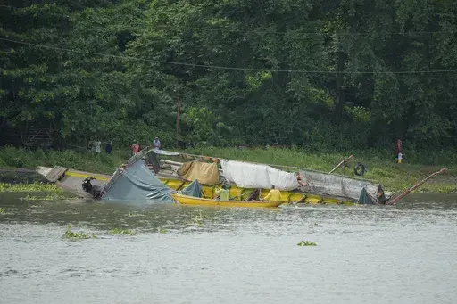 People inspect a capsized ferry in Binangonan, Rizal province, Philippines, Friday, July 28, 2023. The boat turned upside down on Thursday when passengers suddenly crowded to one side in panic as fierce winds pummeled the wooden vessel, killing a number of people, officials said Friday. (AP Photo/Aaron Favila)