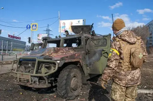 A Ukrainian soldier inspects a damaged military vehicle after fighting in Kharkiv,  Ukraine, Sunday, Feb. 27, 2022. The city authorities said that Ukrainian forces engaged in fighting with Russian troops that entered the country's second-largest city on Sunday. (AP Photo/Marienko Andrew)