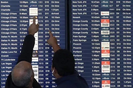 Two men point toward plane arrivals on a flight information board at San Francisco International Airport in San Francisco, Tuesday, Nov. 26, 2019.   Forecasters say, Friday, March 11, 2022,  a powerful, late-winter storm combining rivers of moisture and frigid temperatures is expected to dump snow from the Deep South all the way north to the Canadian border over the weekend that could cause travel problems and power outages across a wide part of the Eastern United States from late Friday through