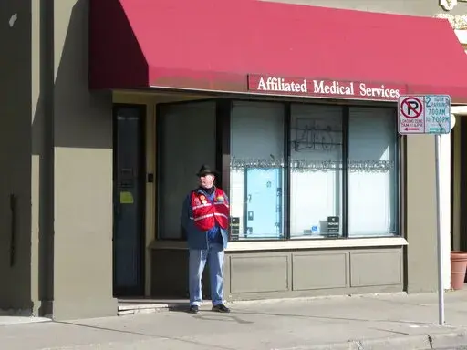 A volunteer escort outside Affiliated Medical Services, a Milwaukee abortion clinic, on Wednesday, May 28, 2014, in Milwaukee. Abortion providers are bracing for the final days of the U.S. Supreme Court's guarantee of a right to an abortion by halting scheduling for the procedure, transitioning staff to help patients travel to other states and creating networks of clinics that will span across regions of the country. Planned Parenthood of Wisconsin, which operates three clinics that provide abor