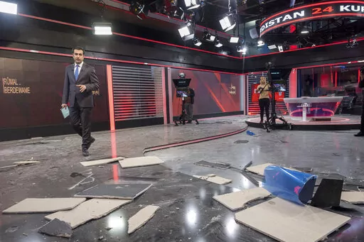 Employees of Kurdistan 24, a satellite television station, work in a studio damaged by an Iranian ballistic missile attack in Irbil, Iraq, Sunday, March 23, 2022. (AP Photo/ Ahmed Mzoori, Metrography)