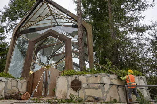 Urban forestry workers remove branches from a redwood tree as they prepare to cut it down next to the Wayfarers Chapel, a sanctuary by architect Lloyd Wright, also known as "The Glass Church," in Rancho Palos Verdes, Calif., Wednesday, May 15, 2024. The modernist chapel features organic architecture with glass walls in a redwood grove overlooking the Pacific Ocean. Part of the Swedenborgian denomination, the church's followers share in 18th-century Swedish scientist and theologian Emanuel Sweden