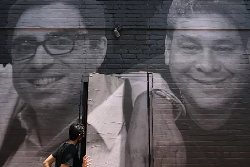 A woman steps through a door that is covered by a mural depicting American hostages and wrongful detainees who are being held abroad, Wednesday, July 20, 2022, in the Georgetown neighborhood of Washington. At left is Siamak Namazi, who has been in captivity in Iran since 2015. At right is Jose Angel Pereira, who has been imprisoned in Venezuela since 2017. Iran has transferred five Iranian-Americans from prison, identifying three of the prisoners as Siamak Namazi, Emad Shargi, and Morad Tahbaz, 