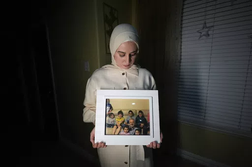 Maryam Kamalmaz hold a photo of her father with some of his 14 grandchildren in Grand Prairie, Texas, Jan. 17, 2024. U.S. officials have developed specific and highly credible intelligence suggesting that Majd Kamalmaz, an American citizen who disappeared seven years ago while traveling in Syria has died, Maryam Kamalmaz said Saturday, May 18. (AP Photo/Julio Cortez, File)