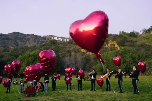 A Mexican Mariachi band surrounded by heart-shaped balloons awaits the arrival of a couple's wedding proposal ceremony at the Lake Hollywood Park in Los Angeles, on Feb. 14, 2022. This is the first Valentine's Day since the U.S. surgeon general issued a public health advisory declaring loneliness and isolation an epidemic with dire consequences. (AP Photo/Damian Dovarganes, File)