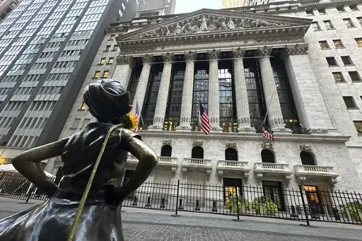 The Fearless Girl statue, with a flower draped on the shoulder, stands outside the New York Stock Exchange on Oct. 23, 2024. (AP Photo/Peter Morgan, File)