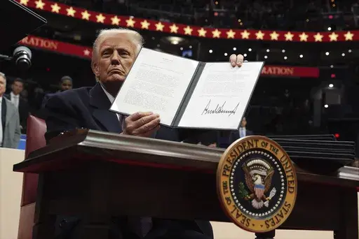 President Donald Trump signs an executive order as he attends an indoor Presidential Inauguration parade event at Capital One Arena, Monday, Jan. 20, 2025, in Washington. (AP Photo/Evan Vucci)