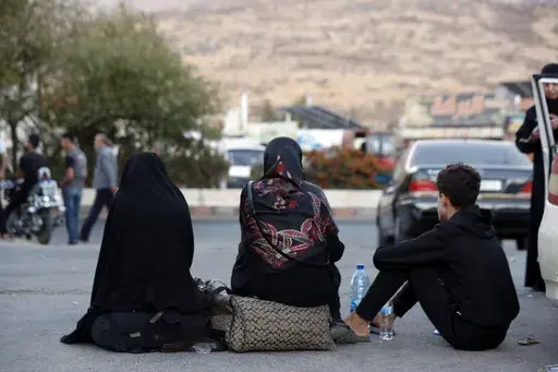 Lebanese fleeing the Israeli bombardment, sit on the ground after crossing into Syria at the Syrian-Lebanese border crossing in Jdaidet Yabous, Syria, Tuesday, Sept. 24, 2024. (AP Photo/Omar Sanadiki)