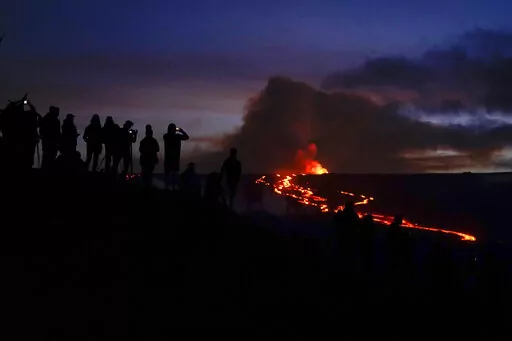People watch and record images of lava from the Mauna Loa volcano Thursday, Dec. 1, 2022, near Hilo, Hawaii. (AP Photo/Gregory Bull)