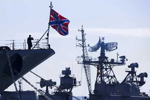 A Russian sailor salutes on the bow of Missile Cruiser Moskva, left, as crew of Russian patrol ship Pitliviy, right, prepare to moor the vessel, in Sevastopol, Crimea, March 30, 2014. The Moskva was built in Ukraine during the Soviet era and now is the flagship of Russia's Black Sea fleet in its war with Ukraine. (AP Photo/Pavel Golovkin, File)
