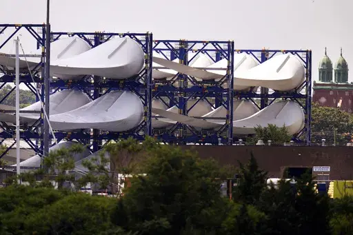 Giant wind turbine blades for the Vineyard Winds project are stacked on racks in the harbor, July 11, 2023, in New Bedford, Mass. Vineyard Wind said Tuesday, July 16, 2024, that it is working to recover debris on Nantucket's southern-facing beaches after one of the wind turbine blades suffered damage last weekend. (AP Photo/Charles Krupa, File)