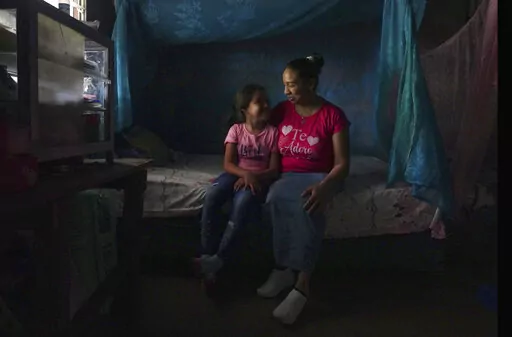 Mariana López sits with her seven-year-old daughter at their home in Ahuachapan, El Salvador, on Thursday, May 19, 2022. In 2000, López says she had an obstetric emergency, but was arrested on suspicion of inducing an abortion. She served 17 years in prison before being released when her 25-year sentence was commuted. (AP Photo/Jessie Wardarski)
