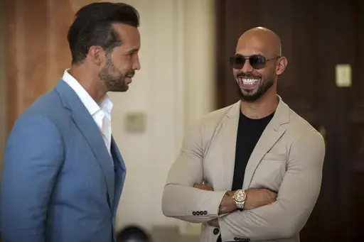 Andrew Tate smiles while waiting along with his brother Tristan, left, for a hearing inside the Court of Appeals building in Bucharest, Romania, Wednesday, June 26, 2024. A court in Romania's capital on Friday, July 5, 2024 ruled that the online influencer Andrew Tate can leave Romanian territory providing he remains within the European Union, as he awaits trial on charges of human trafficking, rape and forming a criminal gang to sexually exploit women. (AP Photo/Vadim Ghirda, File)
