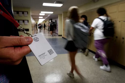 Brent Kiger, Olathe Public Schools' director of safety service, displays a panic-alert button while students at Olathe South High School rush between classes, Aug. 19, 2022, in Olathe, Kan. The district introduced the buttons, which allow staff to trigger a lockdown that will be announced with flashing strobe lights, a takeover of staff computers and a prerecorded intercom announcement, at the start of this school year as part of $2.1 million plan to make district schools more secure. In the wak