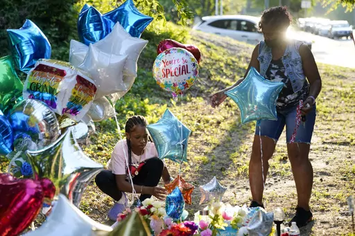 Debbie Jamison, right, with her daughter Precious, 12, leave balloons at a memorial for Cyrus Carmack-Belton, Friday, June 2, 2023, in Columbia, S.C. Authorities said Carmack-Belton, 14, was shot and killed by a store owner who wrongly suspected him of shoplifting. (AP Photo/Erik Verduzco)