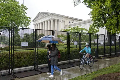 Pedestrians and bikers pass fencing that blocks off the area around the U.S. Supreme Court, Saturday, May 7, 2022, in Washington. A draft opinion suggests the U.S. Supreme Court could be poised to overturn the landmark 1973 Roe v. Wade case that legalized abortion nationwide, according to a Politico report released Monday. Whatever the outcome, the Politico report represents an extremely rare breach of the court's secretive deliberation process, and on a case of surpassing importance. (AP Photo/