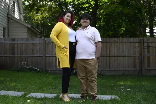 Rousmery Negrón stands with her son at home in Springfield, Mass., on Thursday, Aug. 3, 2023. When in-person school resumed after pandemic closures, Negrón and her son both noticed a change: School seemed less welcoming. Parents were no longer allowed in the building without an appointment, Negrón said. Punishments were more severe. Everyone seemed less tolerant, more angry. Negrón's son even overheard a teacher mocking his learning disabilities, calling him an ugly name. He would end up mis