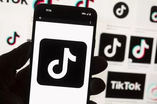 The TikTok logo is displayed on a mobile phone in front of a computer screen, Oct. 14, 2022, in Boston. TikTok will begin labeling content created using artificial intelligence when it's uploaded from certain platforms. TikTok says its efforts are an attempt to combat misinformation from being spread on its social media platform. The announcement came on ABC's “Good Morning America” on Thursday, May 9, 2024. (AP Photo/Michael Dwyer, File)