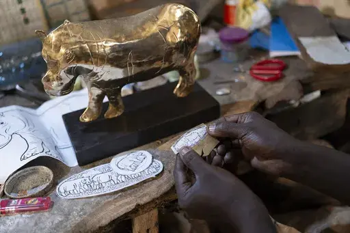 Jeweller Moussa Diop works on a bronze hippopotamus in his workshop, as part of the rebondir exhibition at the Dakar 2024 biennial Off in Dakar, Senegal, Thursday, Nov. 28, 2024. (AP Photo/Sylvain Cherkaoui)