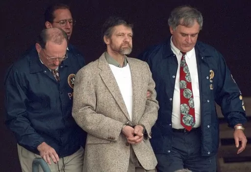 Theodore Kaczynski looks around as U.S. Marshals prepare to take him down the steps at the federal courthouse to a waiting vehicle on June 21, 1996, in Helena, Mont. A spokesperson for the Bureau of Prisons told The Associated Press that Kaczynski, known as the “Unabomber,” has died in federal prison. The cause of death was not immediately known. (AP Photo/Elaine Thompson, File)