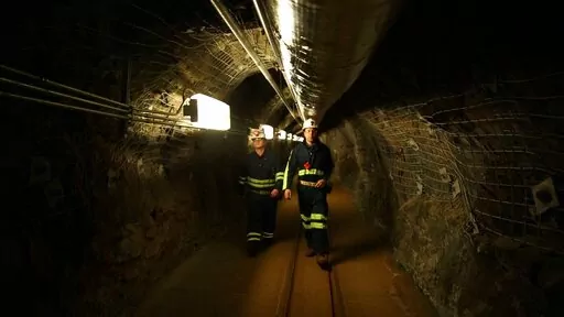 Two researchers walk through an old mining tunnel to what is now the Sanford Underground Research Facility in Lead, S.D., on Dec. 8, 2019. The laboratory houses a dark matter detector.  Scientists have begun a new search for mysterious dark matter in a former gold mine a mile underground. Dark matter makes up the vast majority of the mass of the universe but scientists don't know what it is. (AP Photo/Stephen Groves)